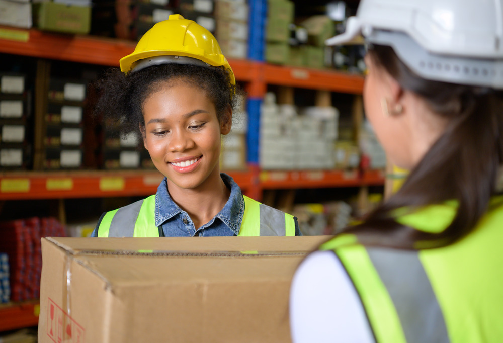 64db7ee5f37b46674e4a283a two girls warehouse workers help each other lift h 2022 09 27 23 16 14 utc201