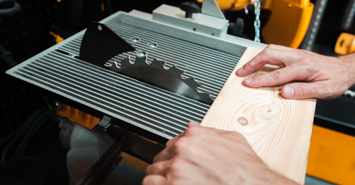 man pushing wood through a table saw