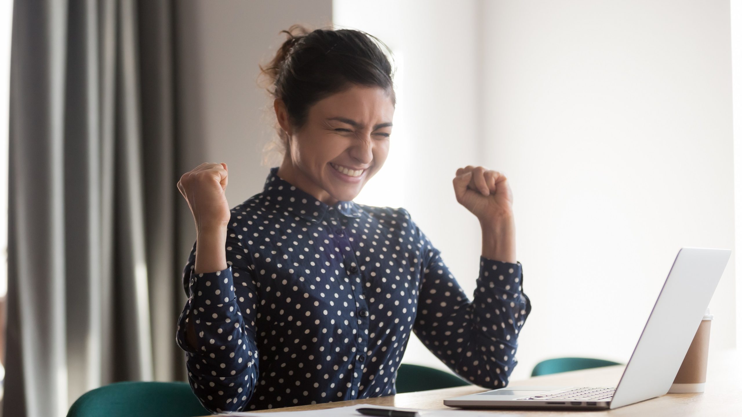 girl with a blue dress celebrating in front of computer